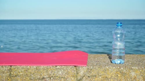 Sports Outdoors. Pink Mat and Water Bottle on Sea