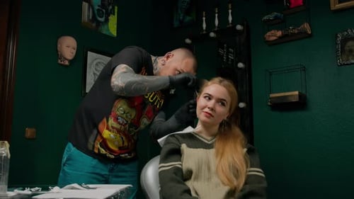 Piercing studio interior - piercing master makes a piercing to a girl, ear piercing