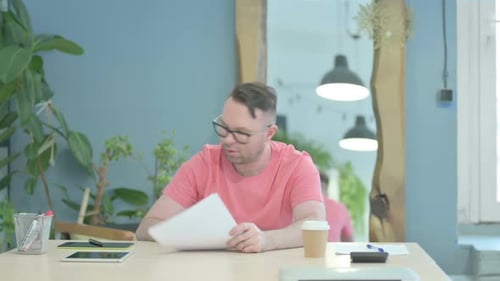 Frustrated Man Reviews Documents in Bright Office