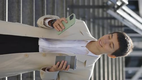 Vertical Video Smiling Business Lady Standing Near Office Building in Formal Suit Using Smartphone