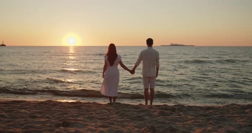 Couple Standing Together on the Beach Holding Hands in Sunset Light