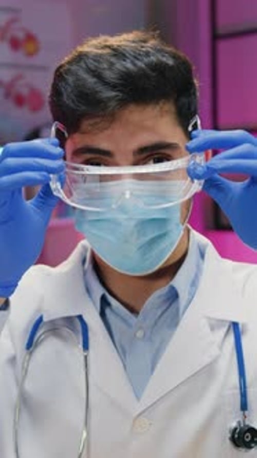 Young Adult Male Medical Worker Puts on Safety Goggles