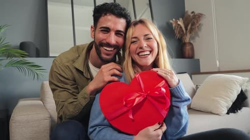Happy Couple Laughing With Heart-Shaped Gift