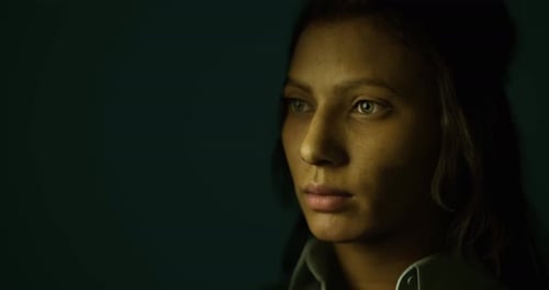 Portrait of a Young Woman with Intense Gaze in a Dimly Lit Setting