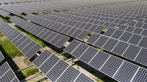 Solar Panels Generating Clean Electricity to Power Nearby City. Low Aerial View