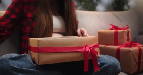 Young Woman Opens Present on Couch Indoors