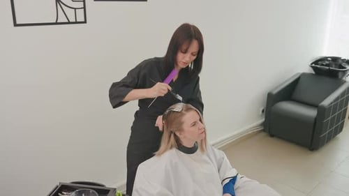 Hair Stylist Colors Blonde Hair in Beauty Salon