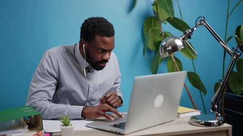 Focused Man Works On Laptop At Desk Indoors