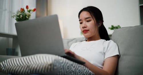 Young Adult Using Laptop on Sofa at Home