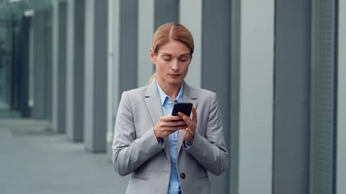 Businesswoman Typing on Mobile Phone Outside Office
