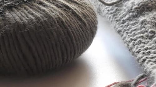 light camera movement to a dark coloured wool - knitting needle stand out of a knitted piece of text