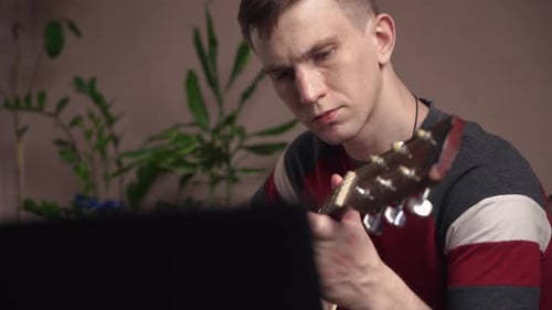 young man is learn.ing to play the acoustic guitar. online learning. close-up