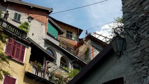 Charming Italian village buildings with balconies and greenery under a clear blue sky