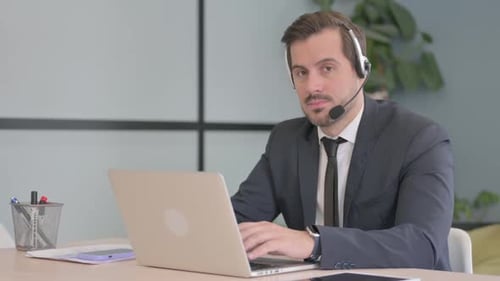 Businessman with Headset Looking toward Camera in Call Center