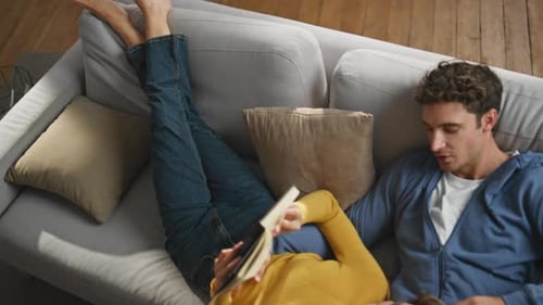 Calm Sweethearts Reading Novel at Grey Sofa Closeup Romantic Man Caressing Wife