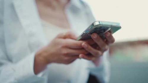 Closeup of young woman holds smartphone in her hands and scrolls through the news feed