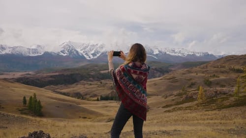 Woman Taking Photo of Snow Capped Mountains