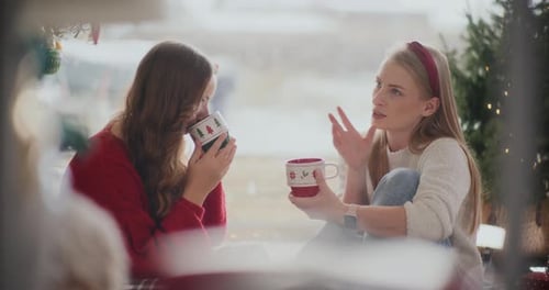 Mujer hablando con su hermana tomando café durante la Navidad en casa