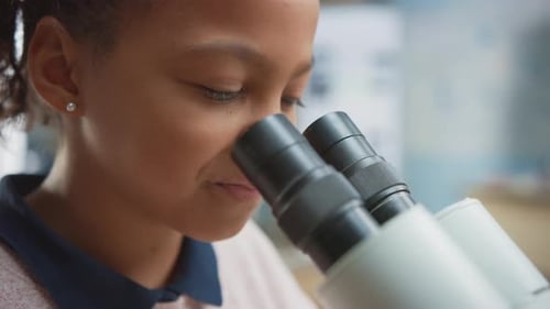 Portrait of Smart Little Schoolgirl Looking Under the Microscope. In Elementary School Classroom Cu