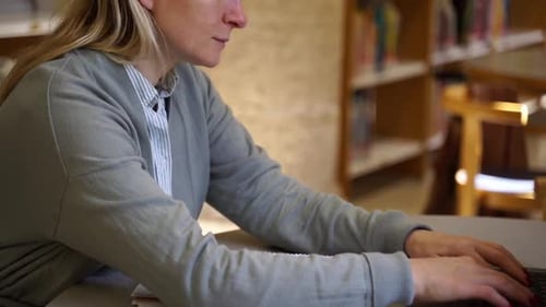 Woman Typing on Laptop in Library