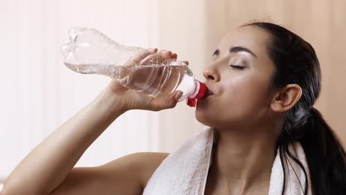 Woman Drinking Water After Exercise Indoors