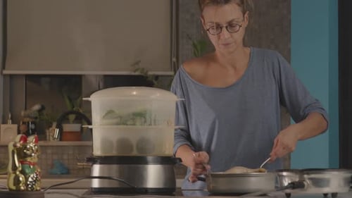 Woman Cooking Food in a Kitchen With Steamer