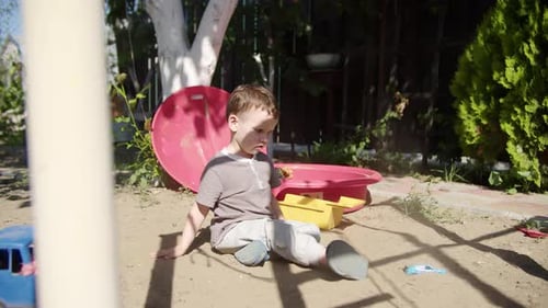 Young Boy Plays With Toys in Sandpit