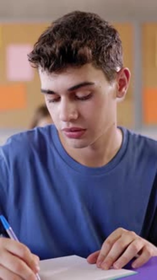 High School Young Student Writing to Notebook in Class Lecture