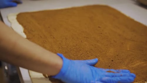 Filling The Dough With Cinnamon Powder Using Hands. close up