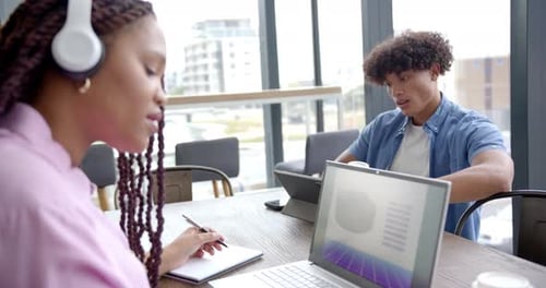 Working in office, colleagues using laptops and taking notes during meeting