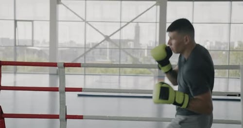 Skilled Boxer Practicing Punches Hitting Air Shadow Fighting in Boxing Ring of Modern Gym