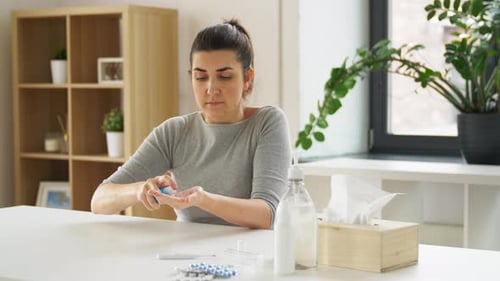 Woman Sanitizes Hands at Table with Medical Supplies