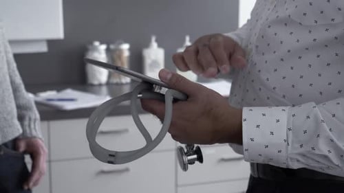 Doctor explains scan results using digital tablet in hospital consultation room