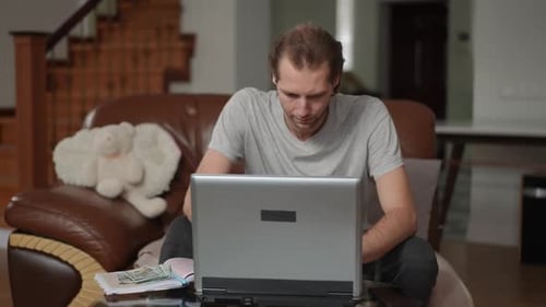 Adult Works on Laptop at Home with Money