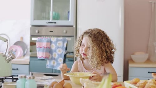 Young Girl Stirring Bowl of Ingredients in Kitchen