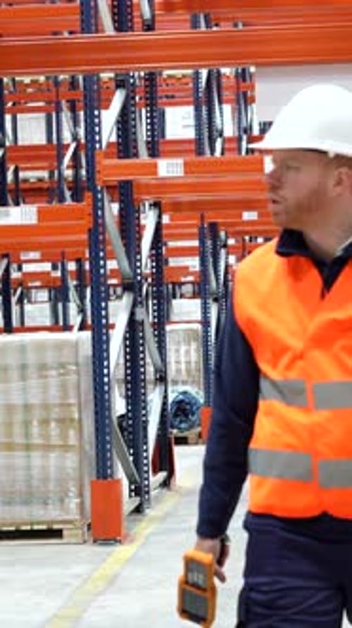 Warehouse worker walking through storage aisles, checking inventory