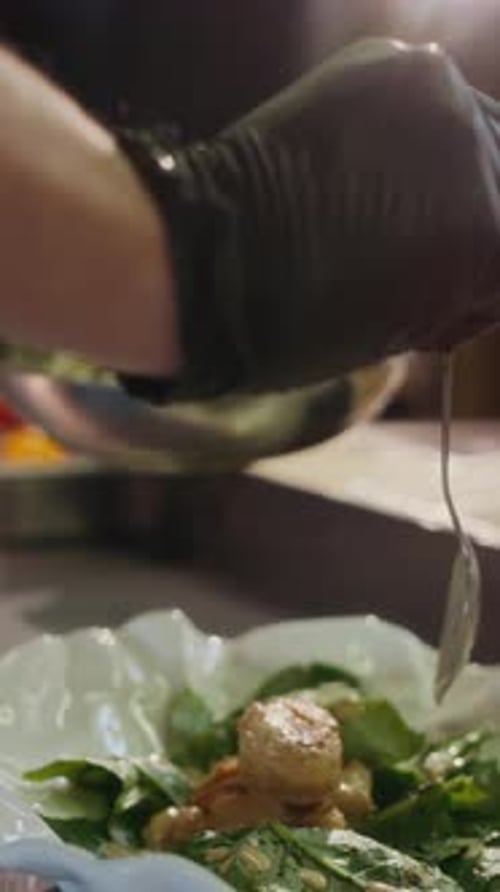 Salad being prepared with dressing in a kitchen