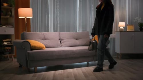 Redhead Tired Woman in Outerwear Walks Up and Falls on the Sofa Without Strenght on the Yellow