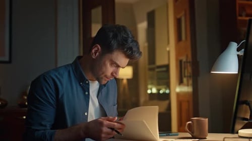 Late Student Flipping Notebook Watching Webinar at Evening Workplace Closeup
