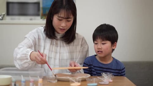 Woman Paints with Young Boy Indoors