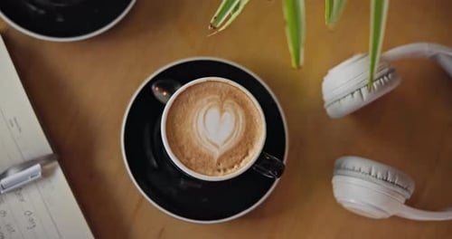 Coffee, notebook and headphones on table, top view and breakfast for cappuccino