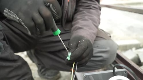 Person Tightens Electrical Wires With a Screwdriver