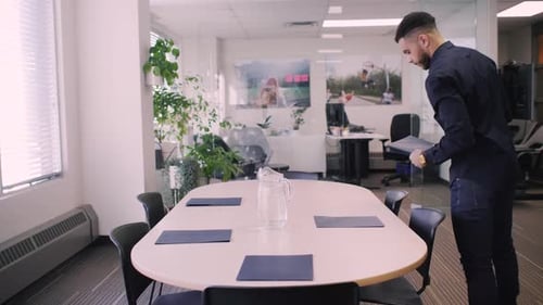 Man Arranging Documents in Bright Modern Office Meeting Room