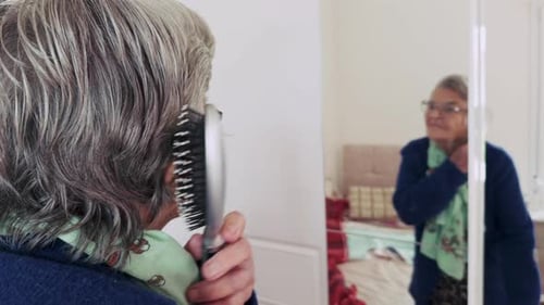 Senior Woman Brushing Her Hair in Mirror