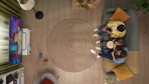Top View of Grandmother Daughter and Grandson on the Sofa Talking Watching TV and Eating Popcorn