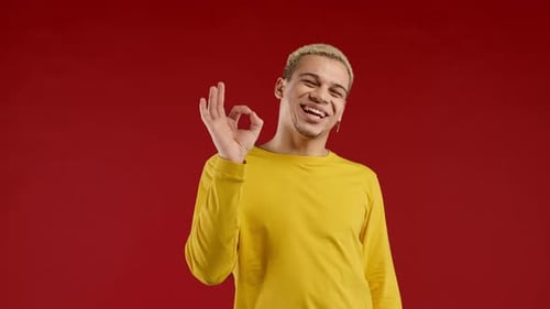 Smiling Young Adult Showing Okay Sign on Red