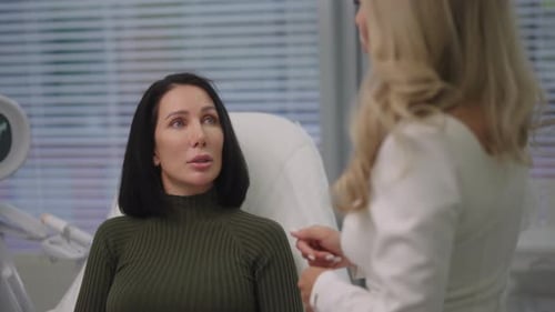 Rear View of Cosmetologist in White Dress Consulting Female Client About Beauty Treatments and