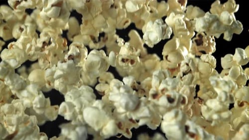 Popcorn fliegt hoch und fällt auf einem schwarzen Hintergrund herunter, gefilmt mit einer Hochgeschwindigkeitskamera mit 1000 Bildern pro Sekunde