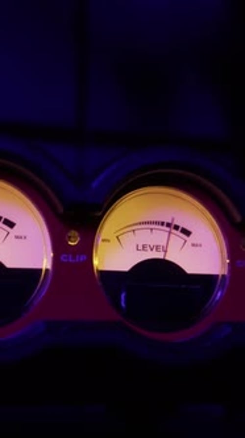 Analoge VU-Meter-Nadeln zur Messung des Audiopegels im dunklen Studio
