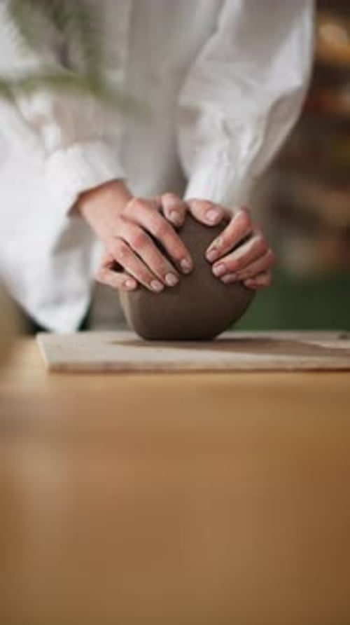 Potter in White Blouse Gently Pressing Clay to Form a Vessel in a Tranquil Pottery Workshop